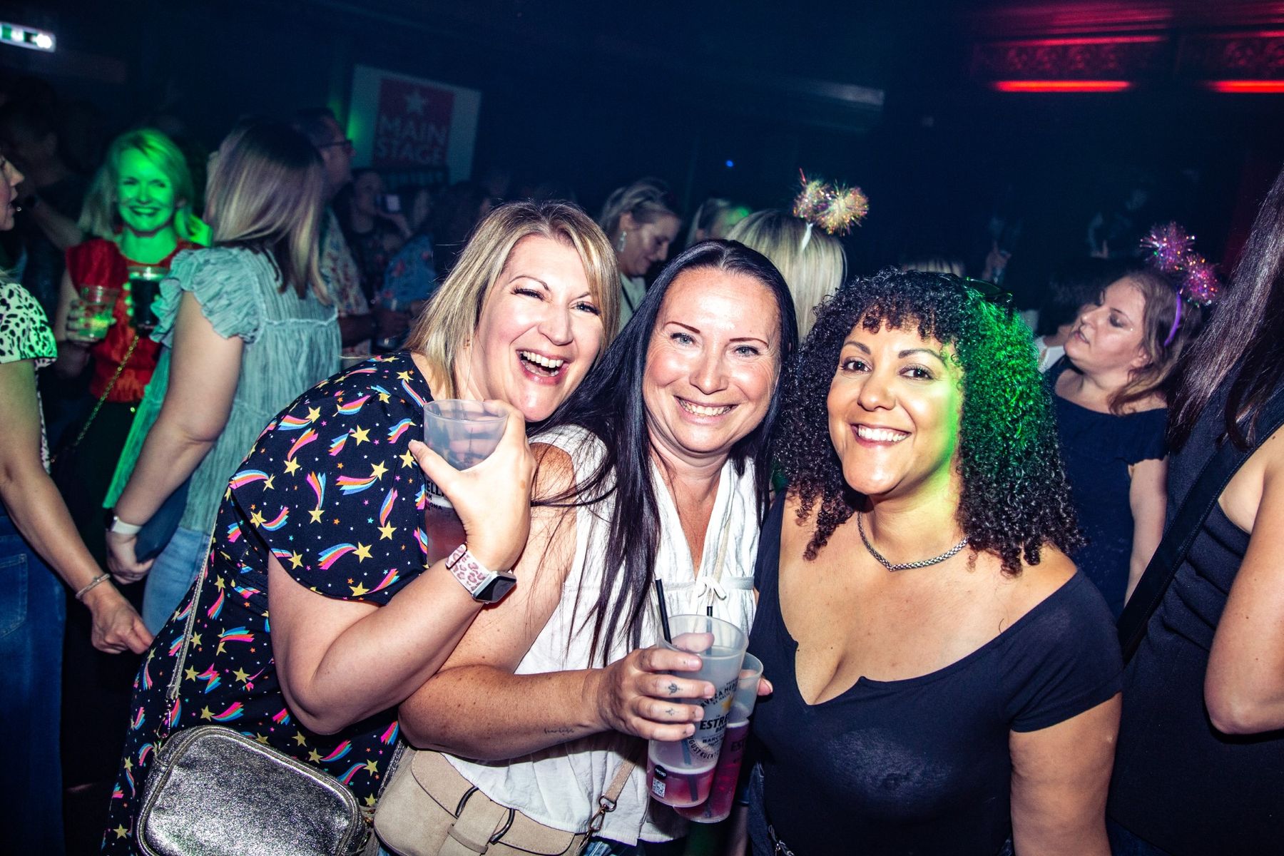 Three friends laughing together on the dancefloor